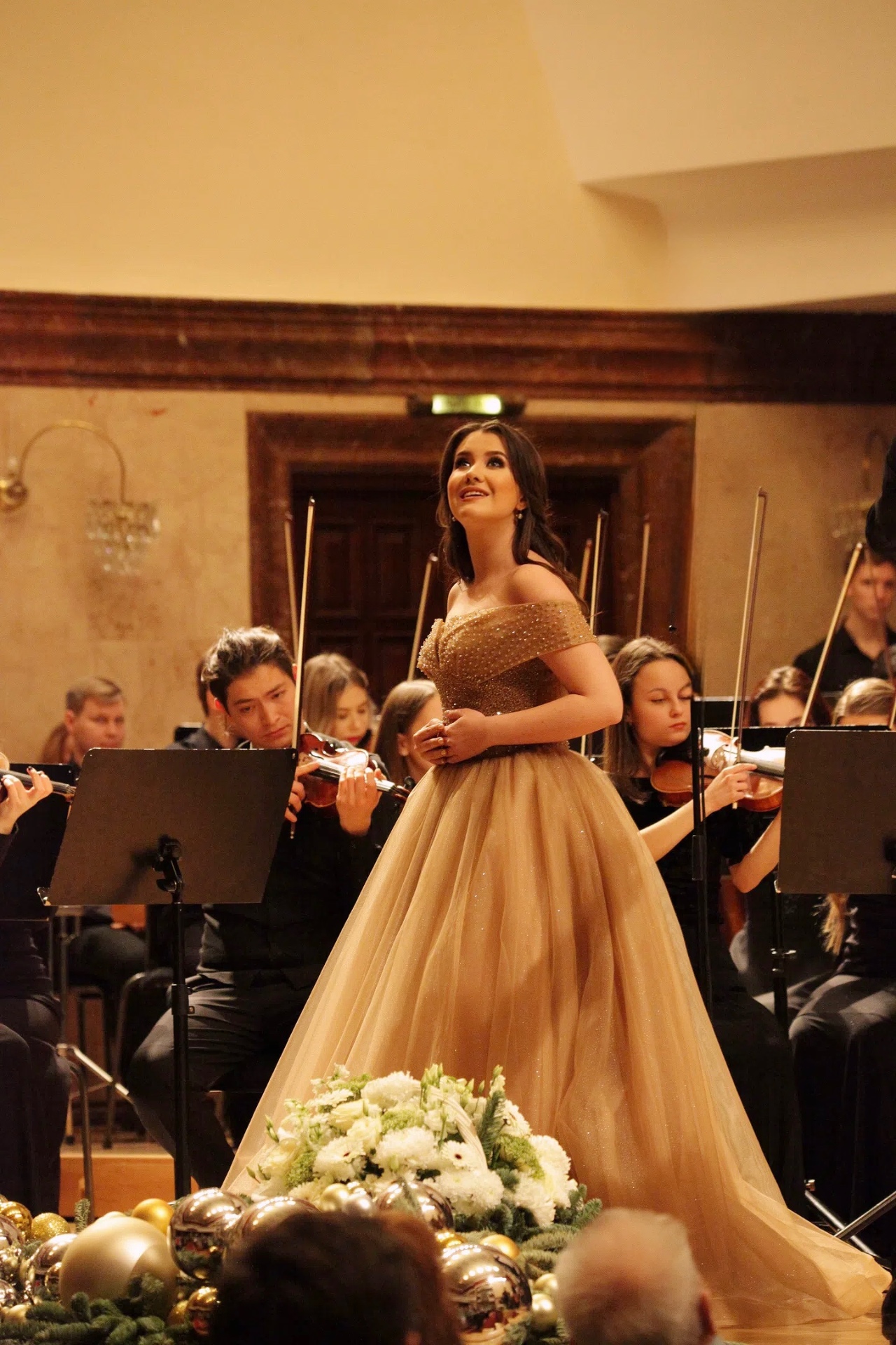 Diliara Tukhvatullina performing with orchestra in a golden gown